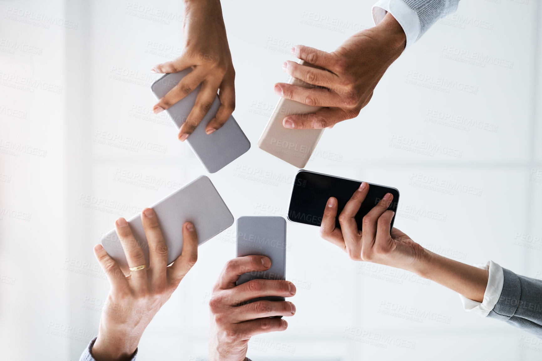 Buy stock photo Hands, phone and business people networking on social media, mobile app or chatting together. Low angle, group and smartphone in circle for online network share, data sync or team communication