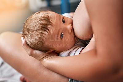 Buy stock photo High angle shot of a young mother breastfeeding her newborn baby at home