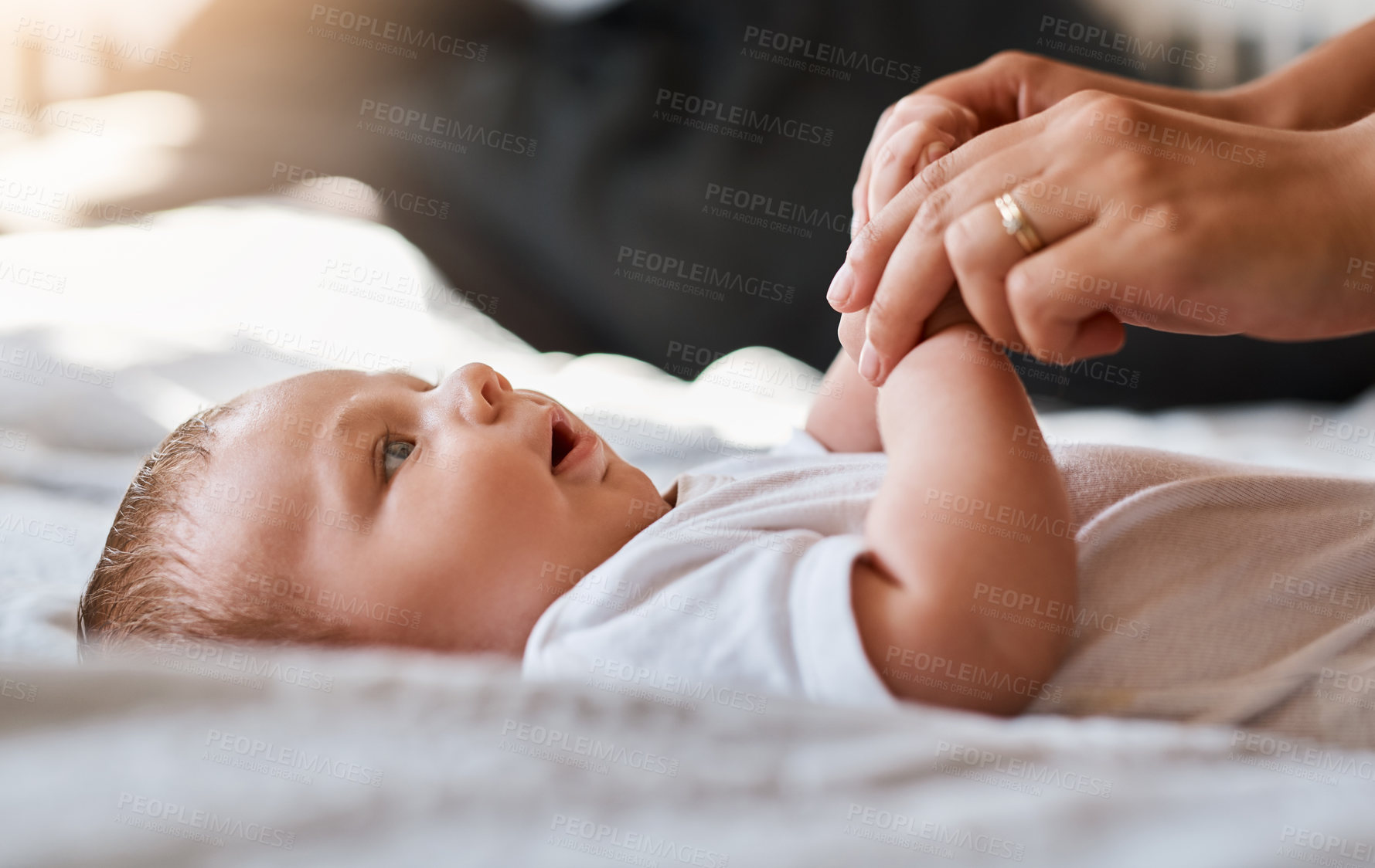 Buy stock photo Hands, parent and baby in bed for care or bonding with trust, love and child development. People, family and toddler or kid as newborn with support, relax and playful for growth and wellness at home