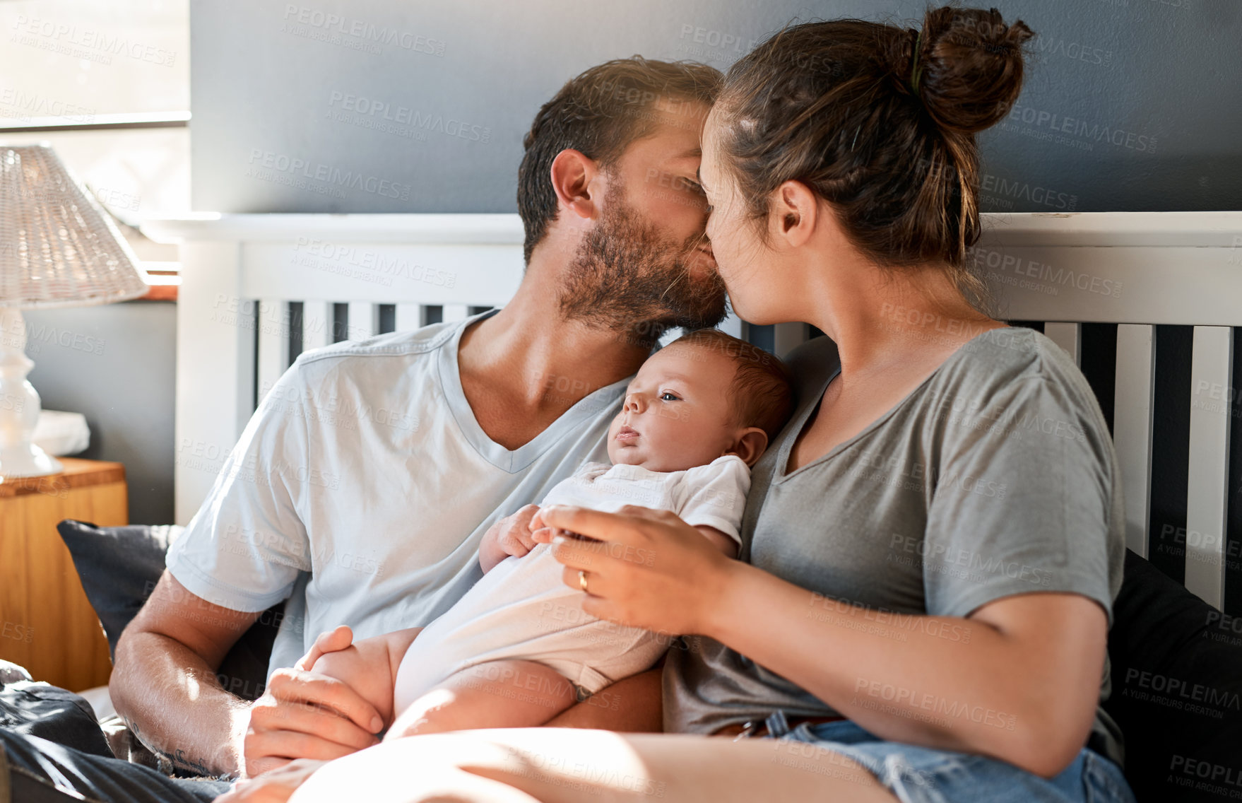 Buy stock photo Shot of a young mother and father bonding with their newborn baby boy in the bedroom
