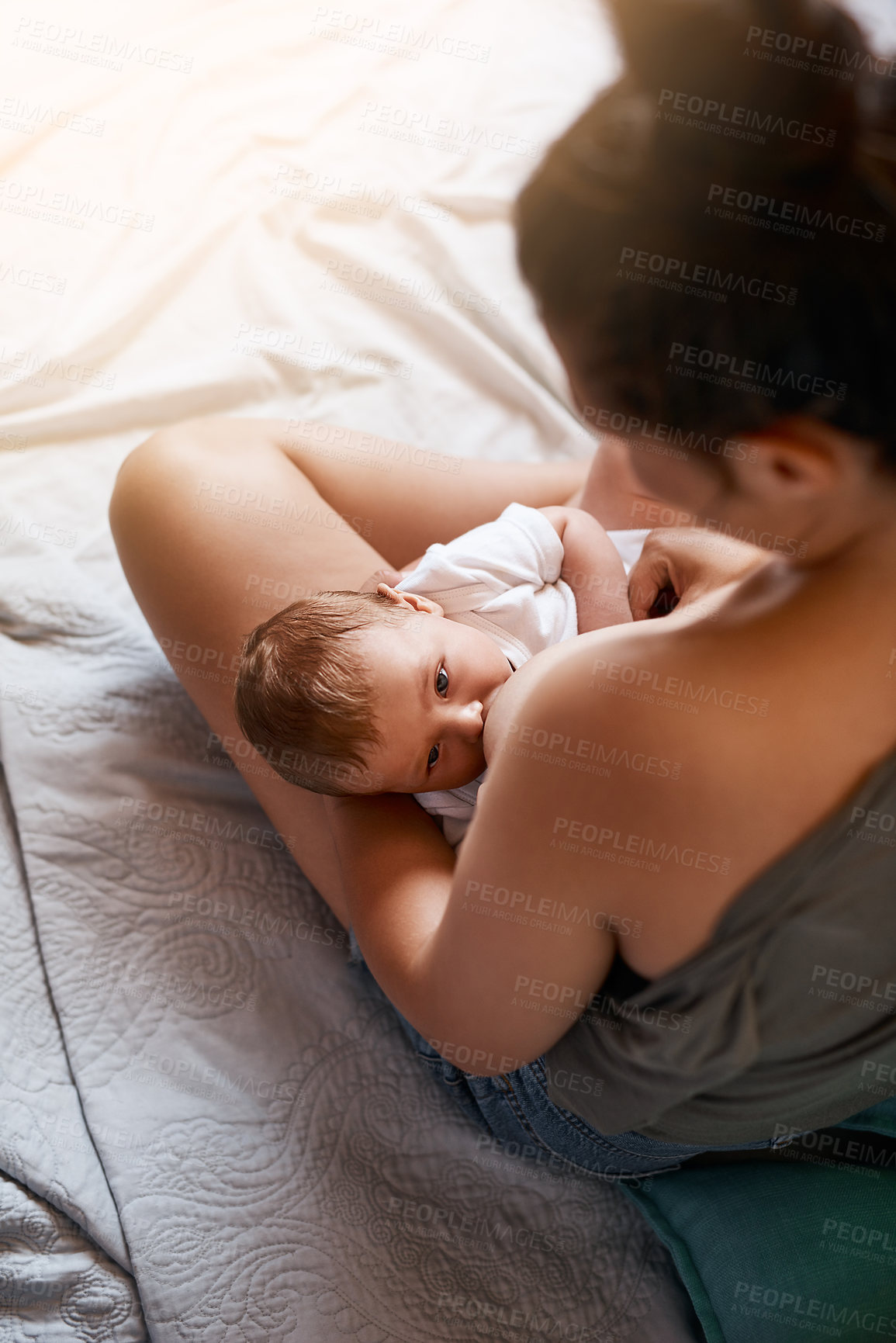 Buy stock photo Mom, baby and breastfeeding on bed in bedroom for growth development, nutrition or digestive health. Lens flare, top view and woman with newborn child for natural milk, wellness or bonding in home