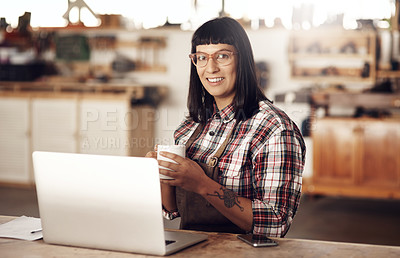 Buy stock photo Cropped portrait of an attractive young woman working on her laptop while sitting in her creative workshop
