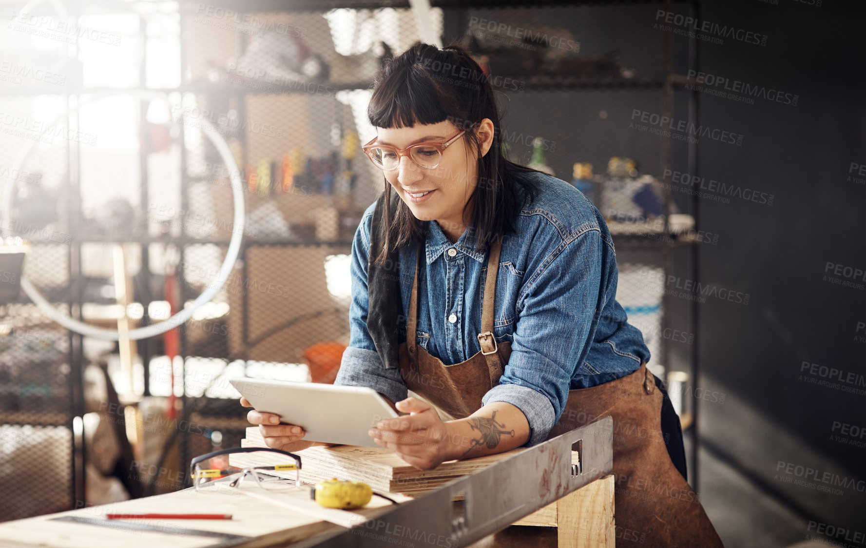 Buy stock photo Cropped shot of an attractive young woman working on her tablet while standing in her creative workshop