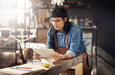 Buy stock photo Cropped shot of an attractive young woman working on her tablet while standing in her creative workshop