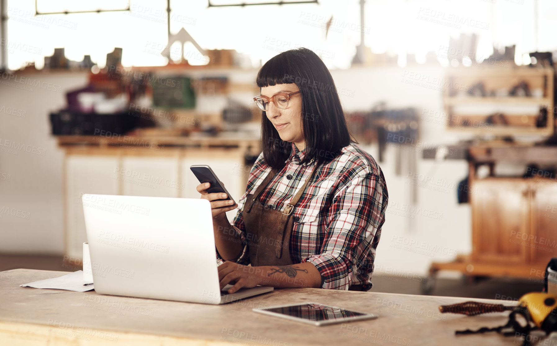 Buy stock photo Cropped shot of an attractive young woman working on her laptop while sitting in her creative workshop