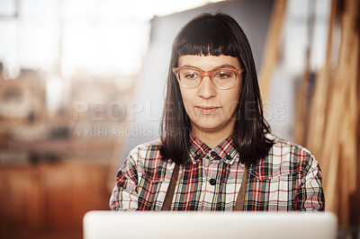 Buy stock photo Cropped shot of an attractive young woman working on her laptop while sitting in her creative workshop