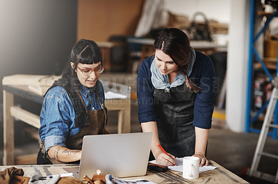 Buy stock photo Cropped shot of two attractive young creative female artisans working on a laptop in their workshop