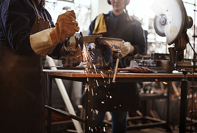 Buy stock photo Cropped shot of two unrecognizable young female artisans using an angle grinder in their workshop