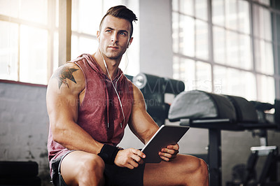 Buy stock photo Cropped shot of a handsome young man using a tablet at the gym