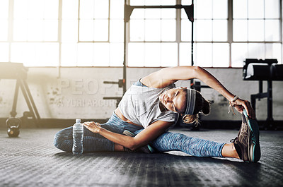 Buy stock photo Shot of an attractive young woman stretching at the gym