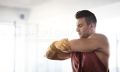 Buy stock photo Cropped shot of a handsome young man stretching at the gym