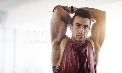 Buy stock photo Cropped shot of a handsome young man stretching at the gym