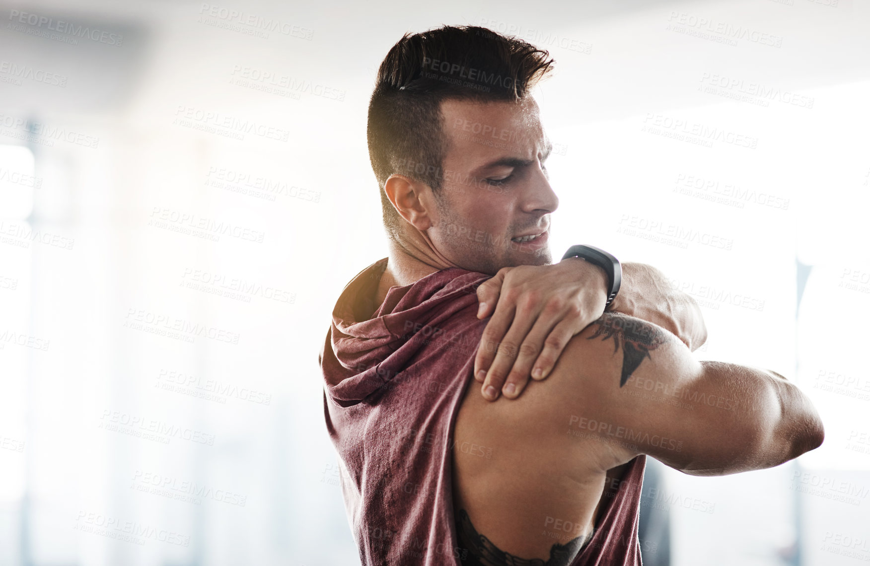 Buy stock photo Cropped shot of a handsome young man stretching at the gym