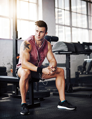 Buy stock photo Shot of a handsome young man taking a break during his workout at the gym