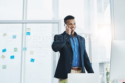 Buy stock photo Shot of a young businessman talking on a cellphone in an office