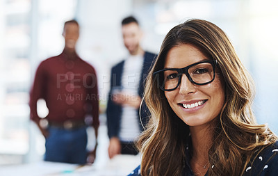 Buy stock photo Cropped portrait of an attractive young businesswoman working in the office with her colleagues in the background