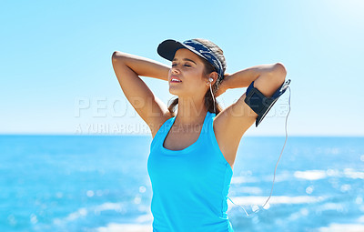 Buy stock photo Shot of a sporty young woman listening to music while out for her workout