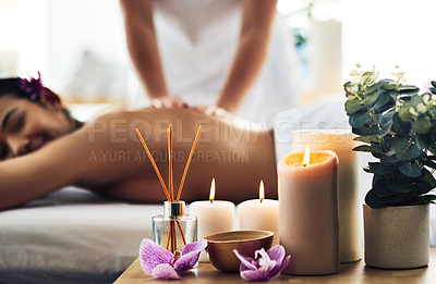 Buy stock photo Shot of spa essentials on a table with a woman getting a massage in the background