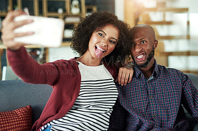 Buy stock photo Shot of a happy young couple taking selfies together at home
