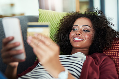 Buy stock photo Shot of a young woman using a mobile phone and credit card on the sofa at home
