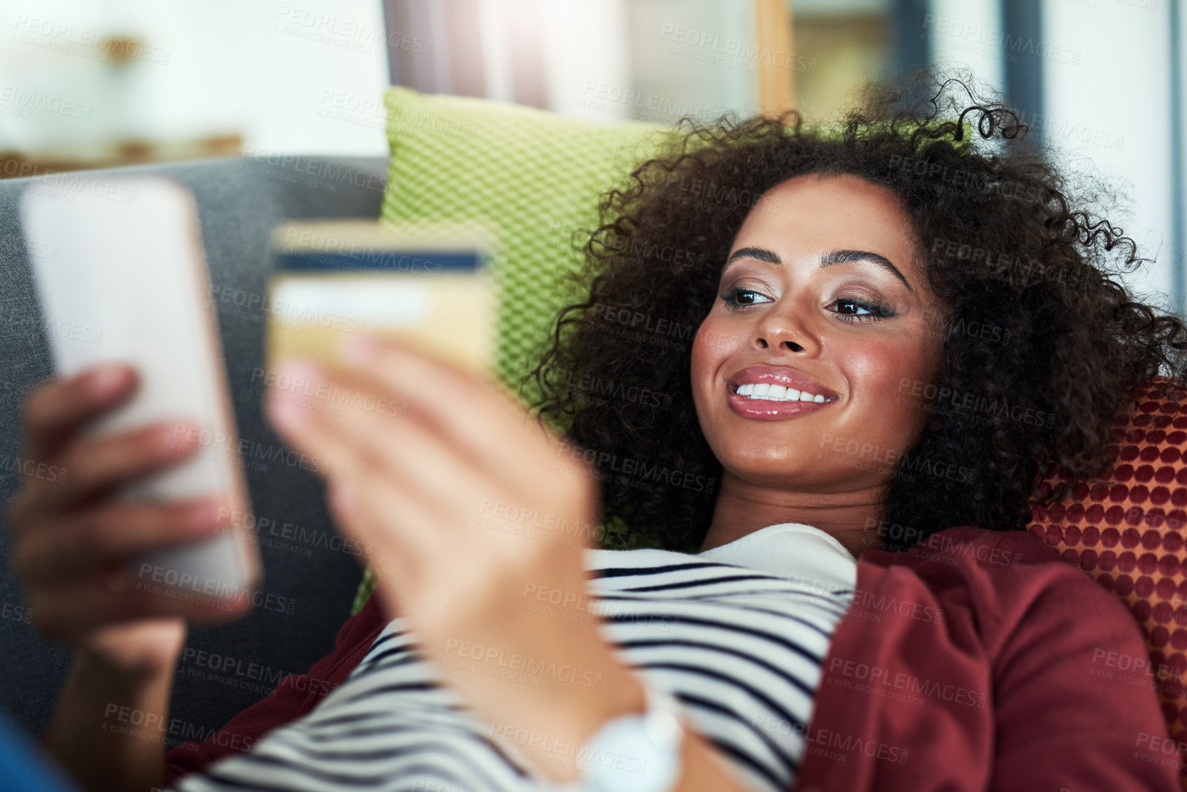 Buy stock photo Shot of a young woman using a mobile phone and credit card on the sofa at home