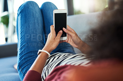 Buy stock photo Shot of a young woman using a mobile phone while relaxing on the sofa at home