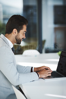 Buy stock photo Shot of a young businessman working on a laptop in an office