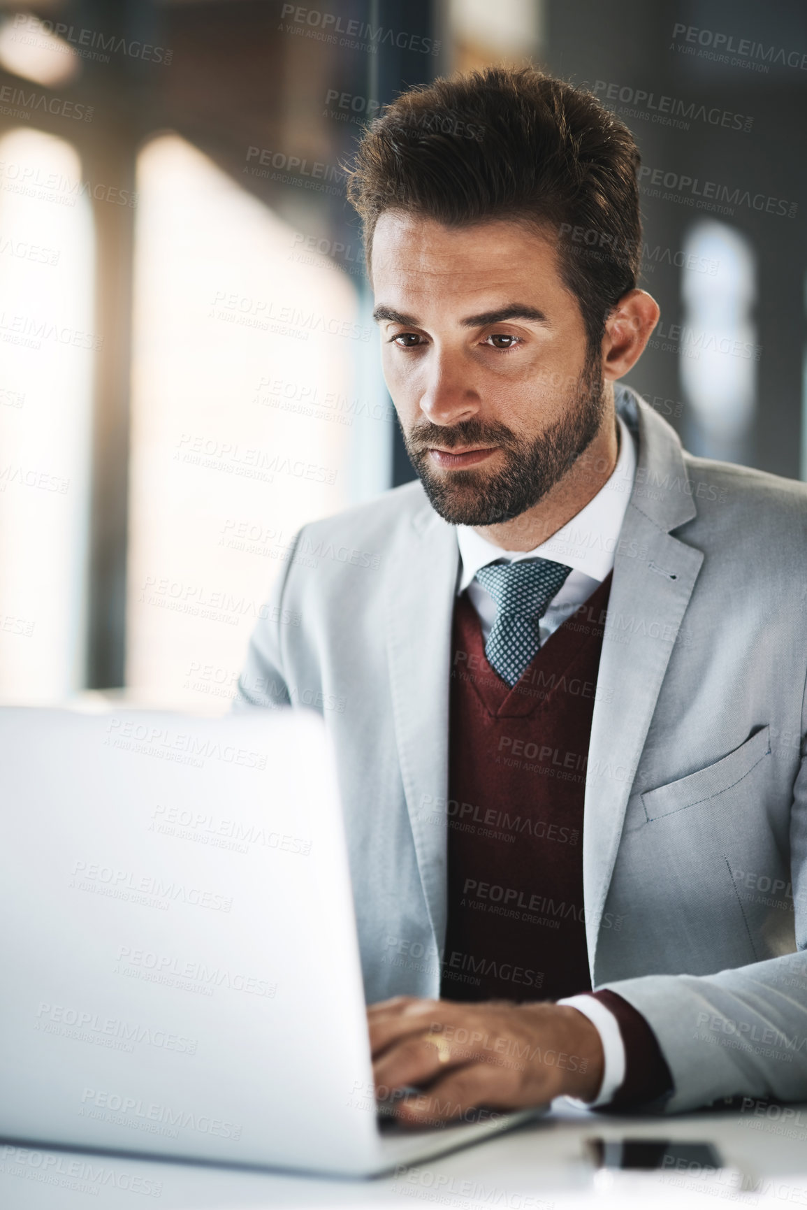 Buy stock photo Shot of a young businessman working on a laptop in an office