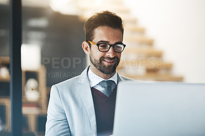 Buy stock photo Shot of a young businessman working on a laptop in an office