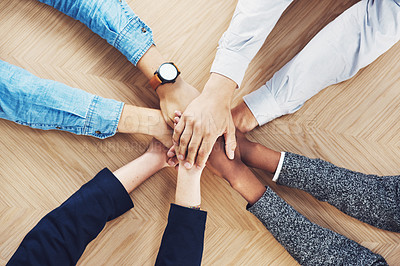 Buy stock photo High angle shot of a group of unidentifiable businesspeople joining their hands together in unity
