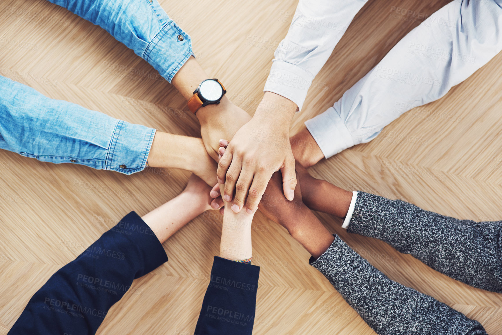Buy stock photo High angle shot of a group of unidentifiable businesspeople joining their hands together in unity