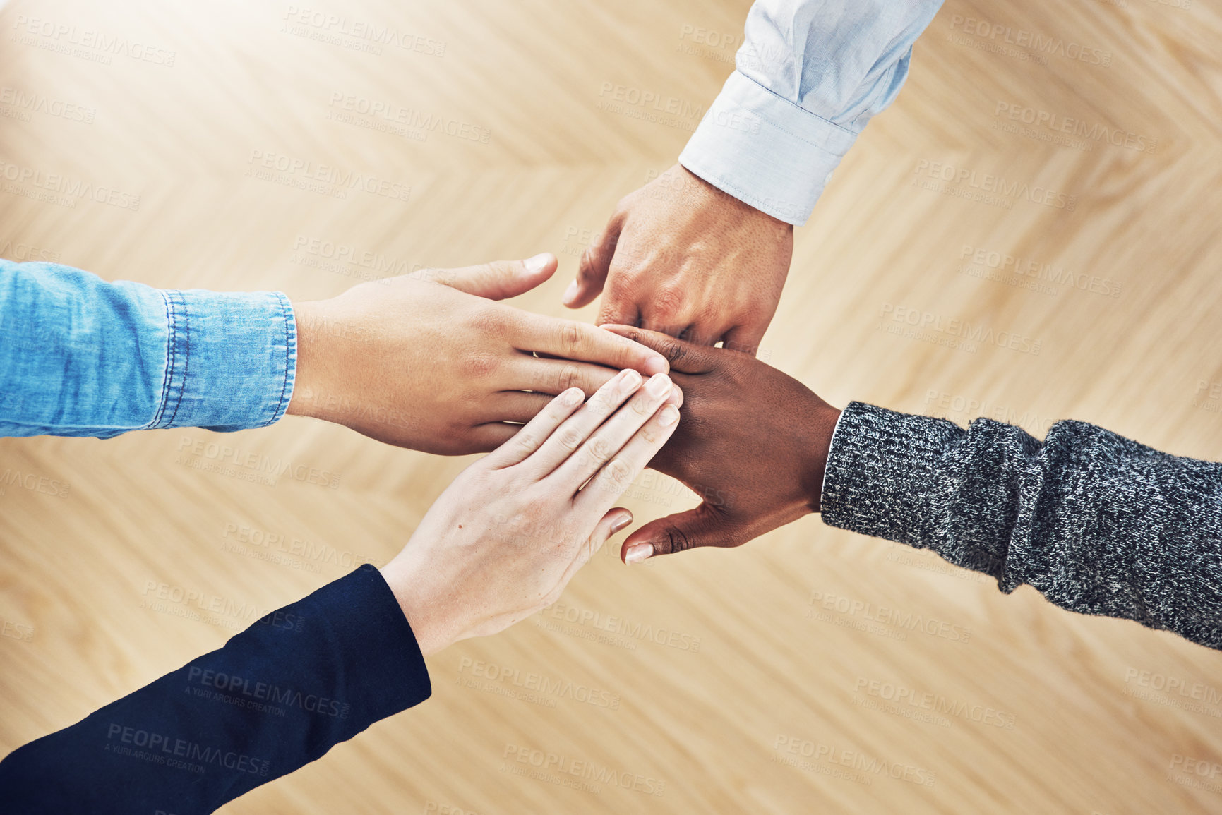 Buy stock photo High angle shot of a group of unidentifiable businesspeople joining their hands together in unity