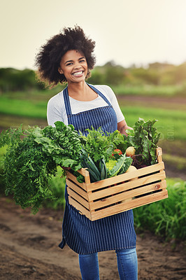 Buy stock photo Shot of an attractive young female farmer carrying a crate of fresh produce