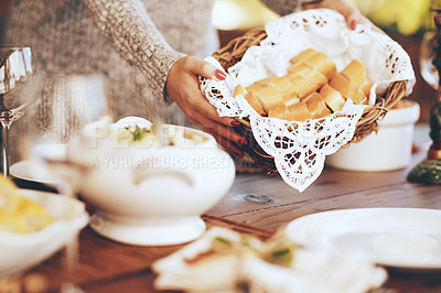 Buy stock photo Woman, bread basket and food at dinner table in home, house and dining room for family lunch, meal and hosting social gathering together. Closeup sliced baguette for party, celebration and eating 
