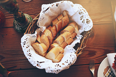 Buy stock photo Bread, food and basket with a starter serving on a wooden dinner table in a home for a celebration event. Party, lunch and mutrition with a baguette on a surface for eating, dining or a meal