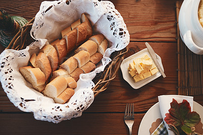 Buy stock photo Table, bread and butter for dinner, lunch or festive celebration for thanksgiving, christmas or birthday. Dining table, food and decoration for party in home, house or restaurant with basket for meal