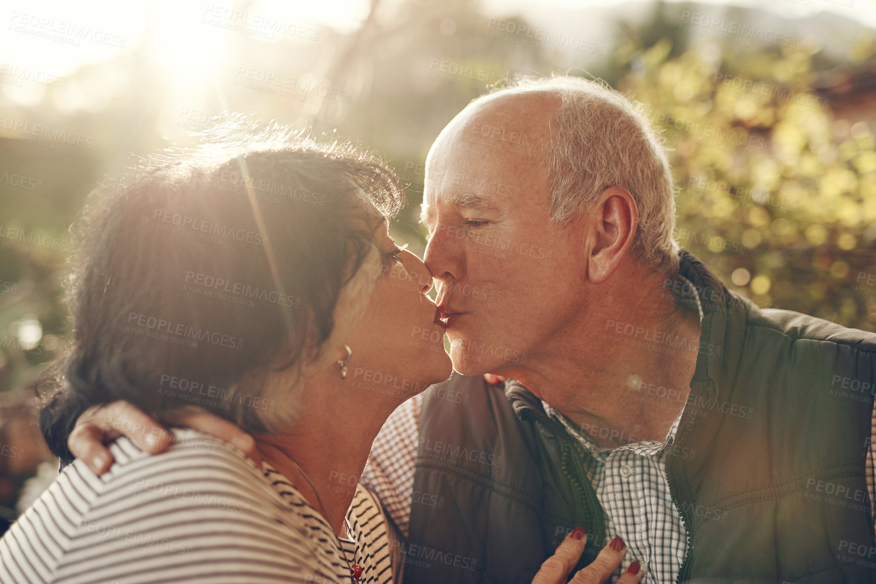 Buy stock photo Kiss, love and senior couple in nature, park or outdoor for retirement wellness, care and life together in summer sunshine. Holiday, travel and elderly people with countryside date or anniversary