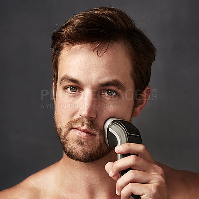 Buy stock photo Cropped portrait of a handsome young man using an electric shaver