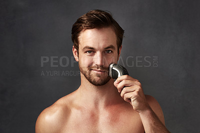 Buy stock photo Cropped portrait of a handsome young man using an electric shaver