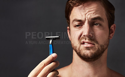 Buy stock photo Cropped shot of a handsome young man holding up a razor blade