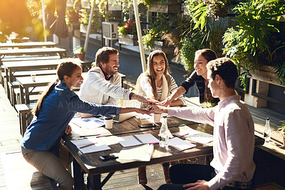 Buy stock photo Cropped shot of a group of colleagues joining hands in agreement during a meeting at an outdoor cafe