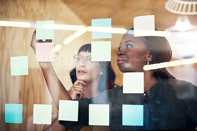 Buy stock photo Women, writing on glass at startup and brainstorming, ideas and planning together in office. Employees, people and teamwork by moodboard with thinking, mindmap or sticky note at creative agency