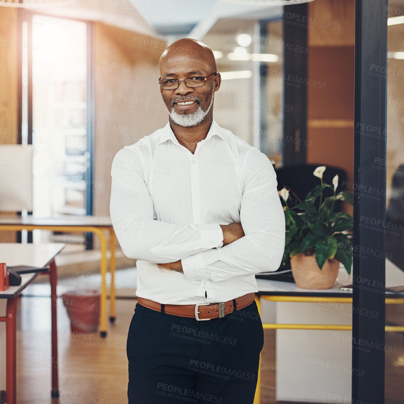 Buy stock photo Portrait of a mature businessman standing with his arms crossed in an office