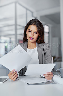 Buy stock photo Cropped shot of a young businesswoman looking through some paperwork in an office