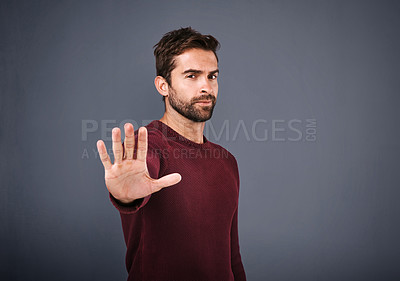 Buy stock photo Studio shot of a handsome young man gesturing to stop against a gray background