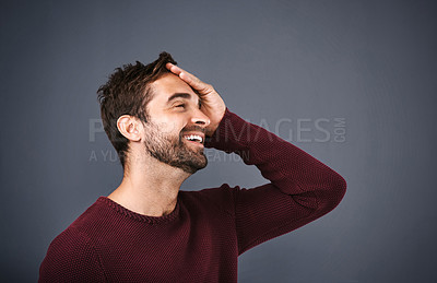 Buy stock photo Studio shot of a handsome young man looking relieved against a gray background