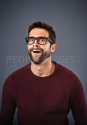 Buy stock photo Studio shot of a handsome young man pulling funny faces against a gray background