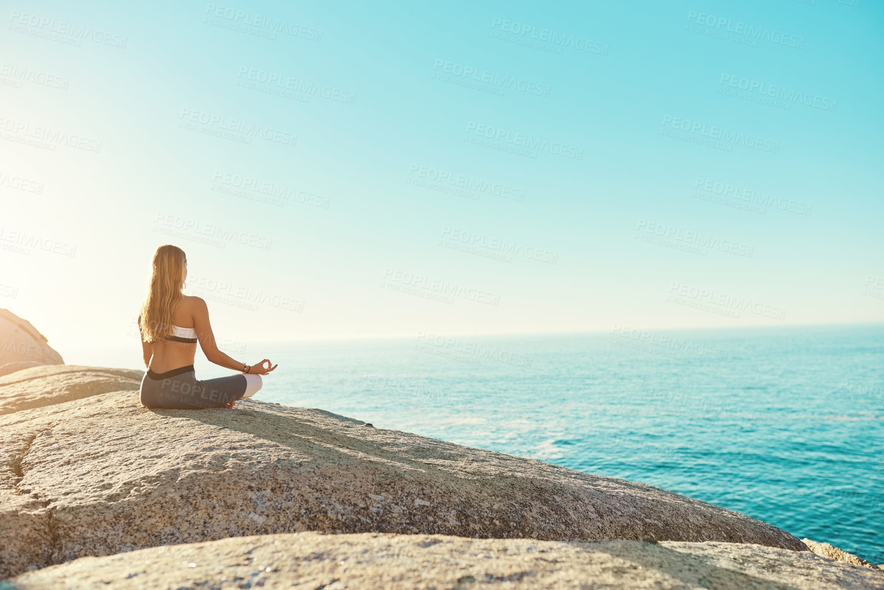 Buy stock photo Rearview shot of a young woman practicing yoga on the beach