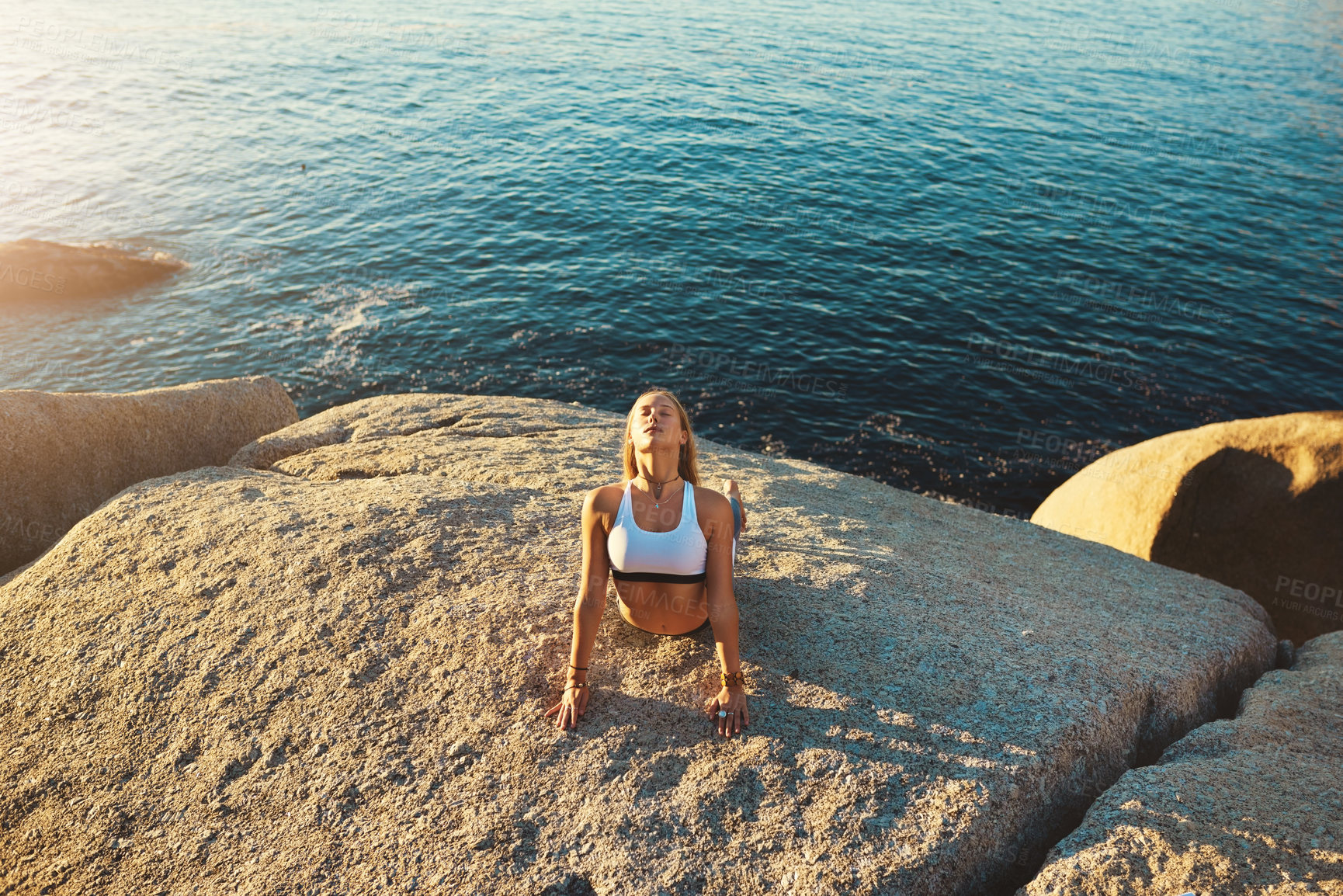 Buy stock photo Shot of an athletic young woman practicing yoga on the beach