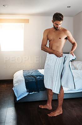 Buy stock photo Full length shot of a handsome young man wrapping himself in a towel in his bedroom at home